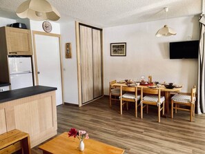 Eine kompakte Küche mit Holdekor, ein Essbereich mit Holztisch und -stühlen sowie eine kleine Sitzecke mit einer Bank.