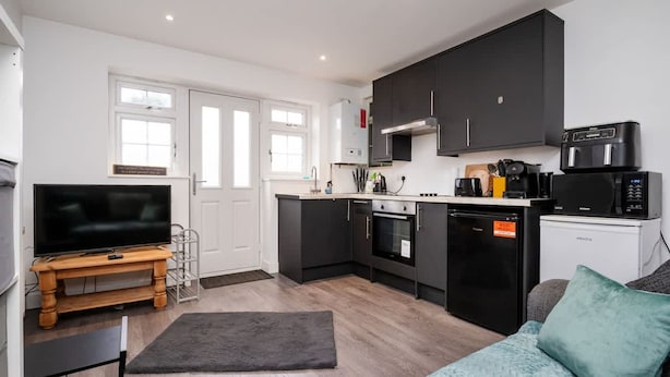 A compact living space with a kitchenette, a television, a sofa, and a coffee machine. - Relaxing Annexe With Garden Access Parking (Maidstone)