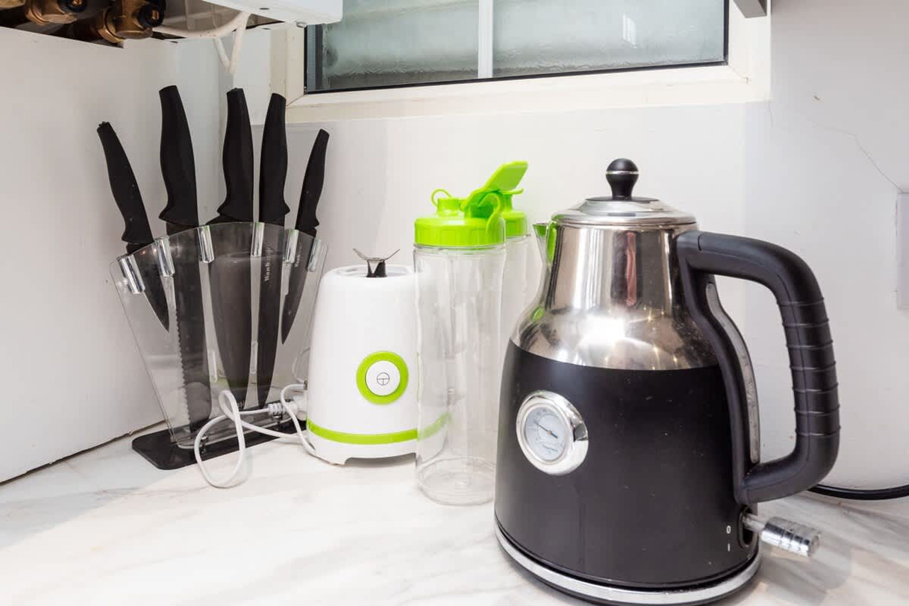 Et køkken med elkedel, blender og knivholder.