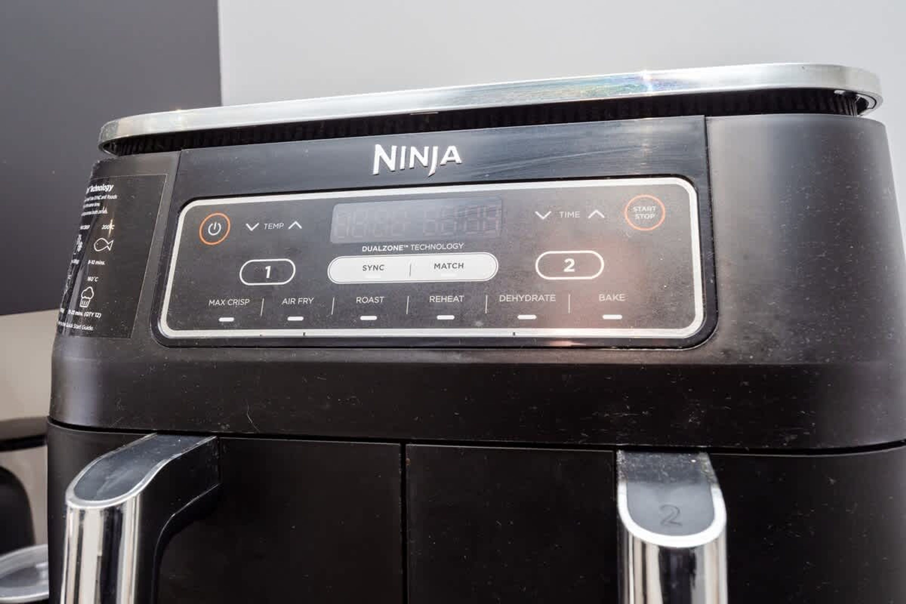 A black Ninja coffee maker with a digital display, buttons for functions like sync, match, and time, and a dualzone technology label.