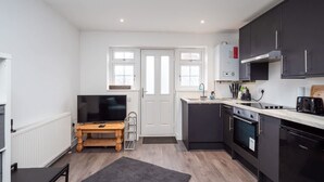 A compact kitchen with a TV, a wooden table, and a small dining area. - Relaxing Annexe With Garden Access Parking (Maidstone)