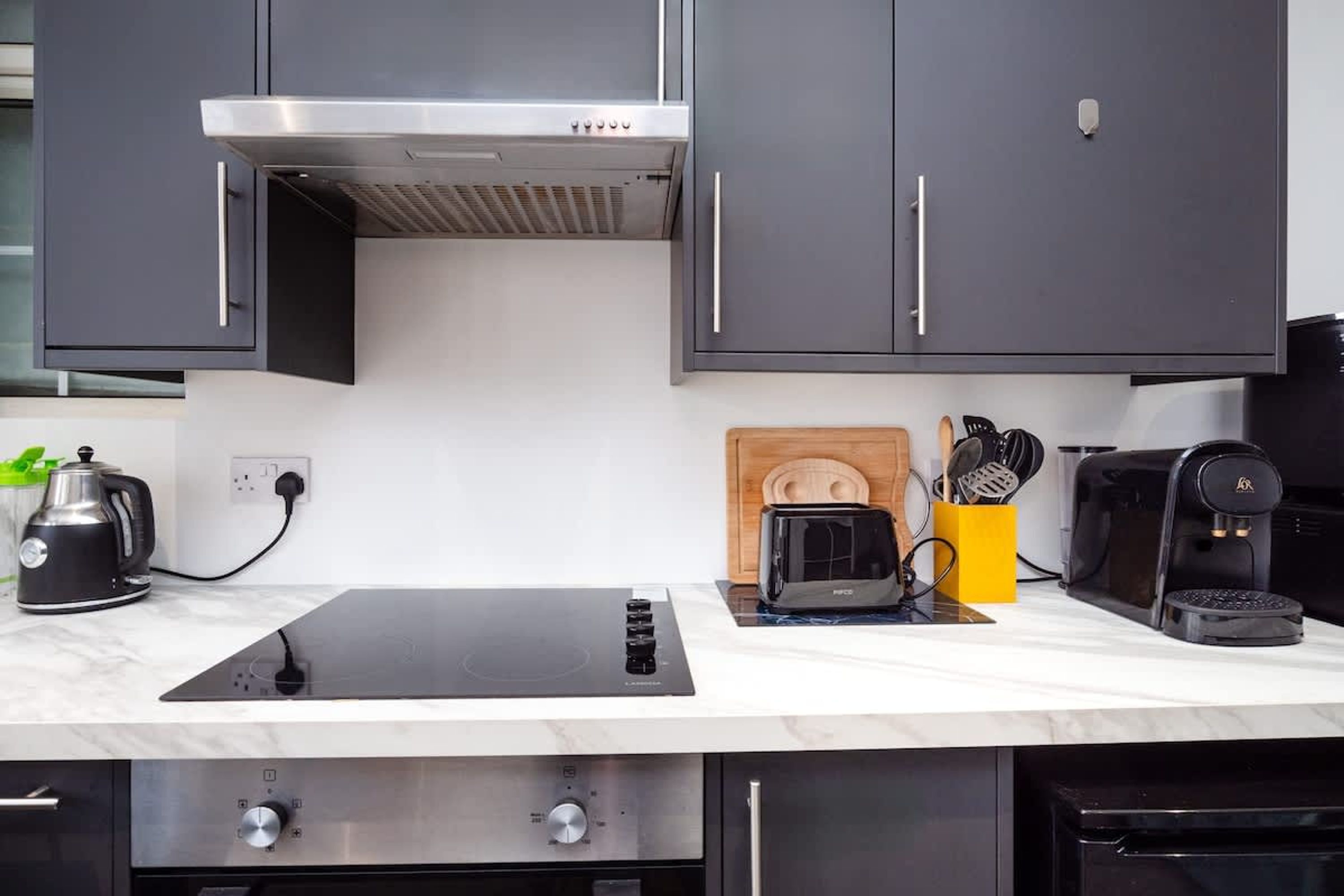 A modern kitchen with a black countertop, a built-in stove, a toaster, and a coffee maker.