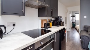 A modern kitchen with black cabinets, a built-in stove, and a coffee machine. - Relaxing Annexe With Garden Access Parking (Maidstone)