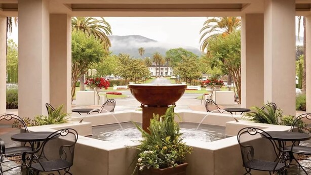 A covered outdoor area with a central fountain, surrounded by tables and chairs, and a view of a building and trees. - 2BR Napa Getaway Side-by-side Condos Golf View (Napa)