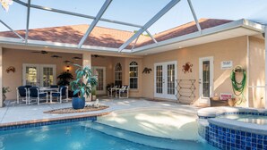 A covered pool area with a hot tub, lounge chairs, and a dining table. - Villa Pearl 4-bedroom Poolhome Close To Ocala (Inverness)