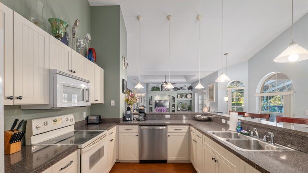 A kitchen with white cabinets, a stainless steel dishwasher, granite countertops, and pendant lighting. - Villa Pearl 4-bedroom Poolhome Close To Ocala (Inverness)