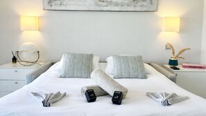 A neatly made bed with pillows, a bedside table with a lamp, a book, and a decorative vase. - Elegant Retreat Near Monaco Private Terrace (Beausoleil)