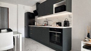 Una cocina moderna con armarios oscuros, microondas integrado y cafetera.