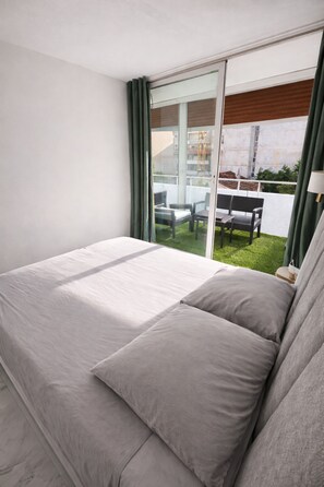 Ein Schlafzimmer mit einem großen Bett, einer Schiebetür zum Balkon und Blick ins Freie.