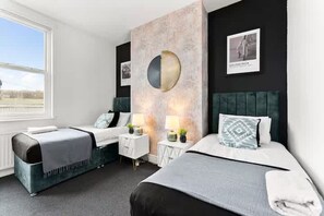 Ein Hotelzimmer mit zwei Betten, einem großen Fenster, einer Wandleuchte und einem gerahmten Bild.
