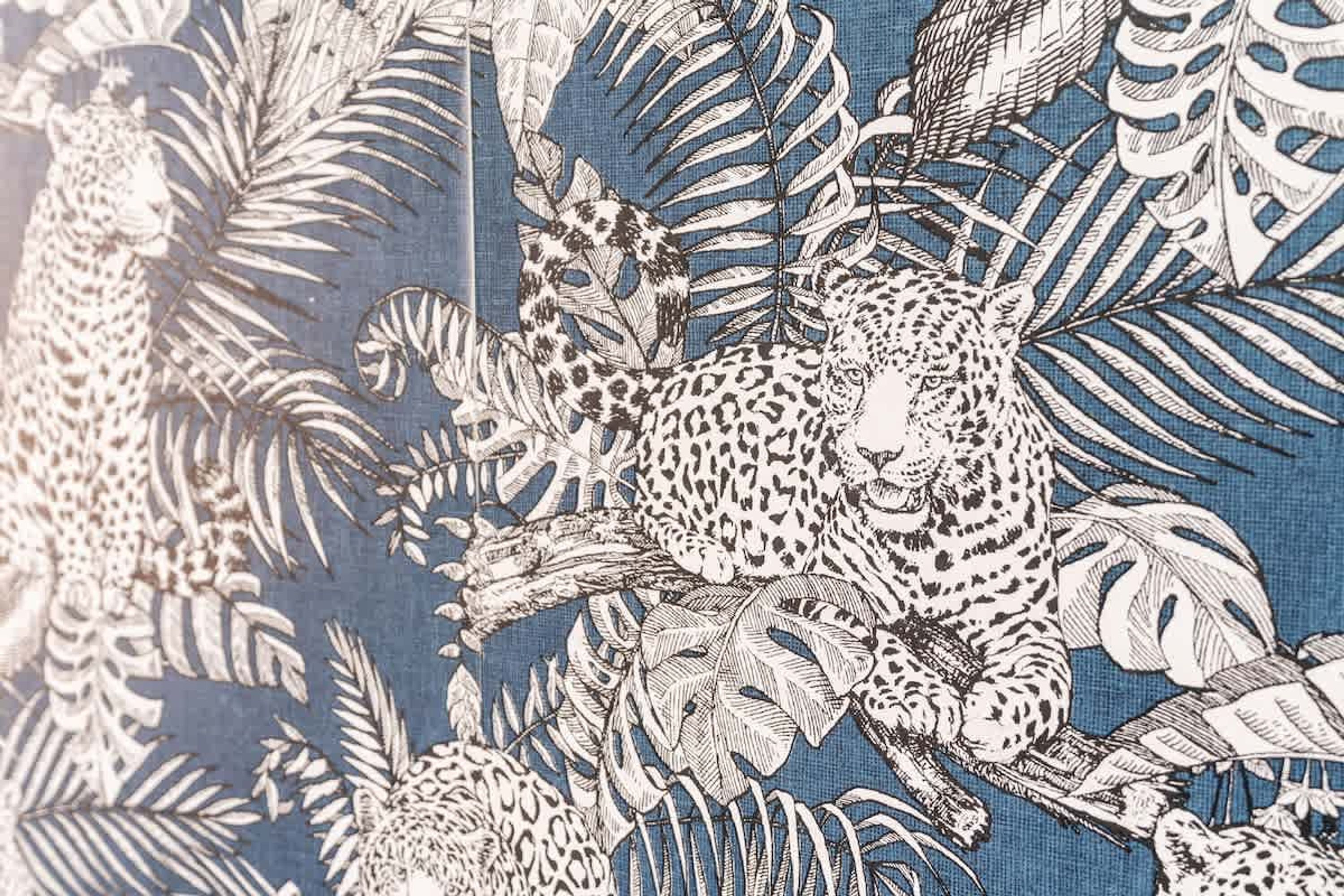 Padrão detalhado com onças e folhagem tropical em tecido.