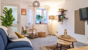 A living room with a sofa, a chair, a coffee table, a lamp, a TV, and a plant. - Perfect Booking 2 Bed Home in Hitchin (Hitchin)