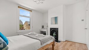 A bedroom with a bed, a fireplace, a window, and a door. - Big Family Home Free Parking Fast Wifi Garden (Kingston Upon Thames)