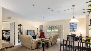 Uma sala de estar com sofá, cadeiras, mesa de jantar e televisão.