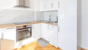 A modern kitchen with white cabinets, a stainless steel sink, a built-in oven, and a marble backsplash. - Amazing Sea View T2- Near Monaco (Beausoleil)