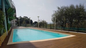 Una piscina rectangular con un deck de madera alrededor, bordeada por una barandilla metálica.