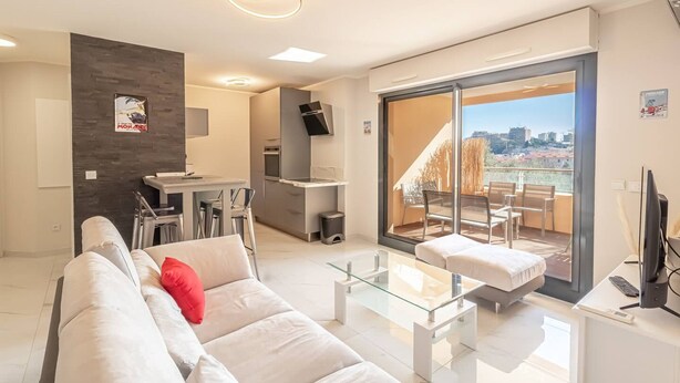 Un apartamento moderno con sala de estar, cocina y balcón con vista a la ciudad.