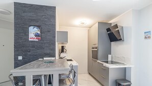 Una cocina moderna con encimera de mármol, electrodomésticos de acero inoxidable y una pared de ladrillo negro.