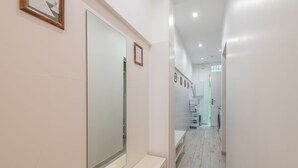 A hallway with a large mirror, a bench, and a door leading to a room with a washing machine. - T2 Splendid View Near Monaco (Beausoleil)