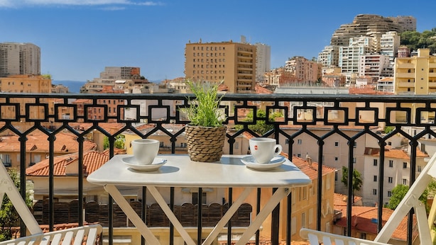 Un balcón con una mesa, dos tazas y una planta en maceta.
