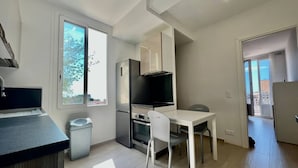 Una cocina compacta con refrigerador, horno y comedor con sillas.
