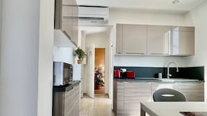 Una cocina moderna con una isla central, electrodomésticos integrados y vistas al comedor.