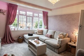 A cozy living room with a sofa, a coffee table, and a window with curtains.
