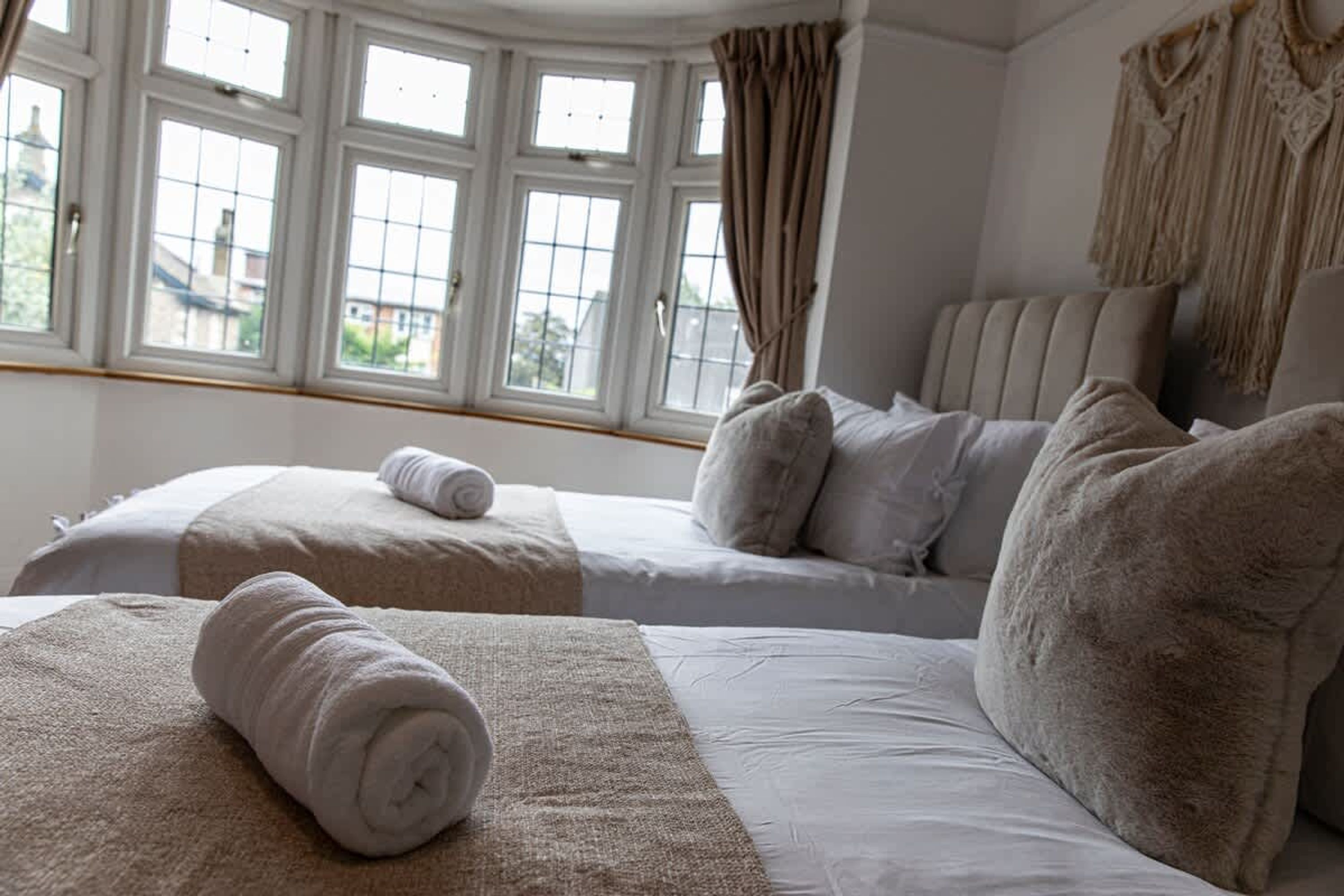 A hotel room with two beds, large windows, and a view of the outside.