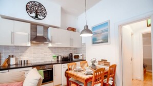 Une cuisine compacte avec des meubles blancs, un four à micro-ondes et un coin repas comprenant une table et des chaises en bois.