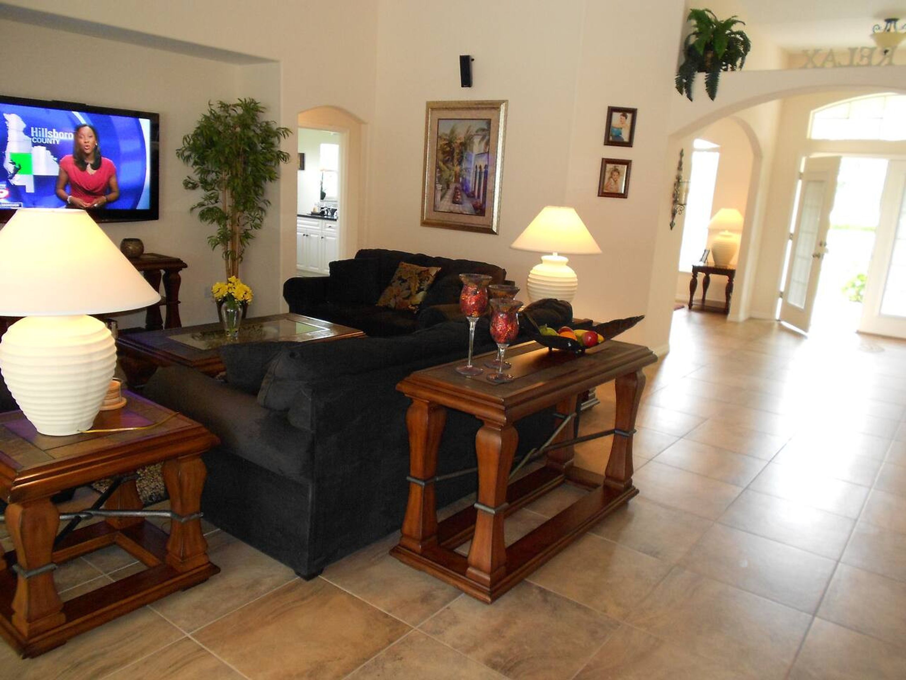 A living room with a television, sofas, lamps, a coffee table, and a painting on the wall.