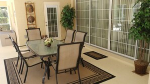 A dining area with a glass table surrounded by chairs, a potted plant, and a decorative wall piece. - Villa Corthouts Luxury Home Close to Bike Trail (Inverness)