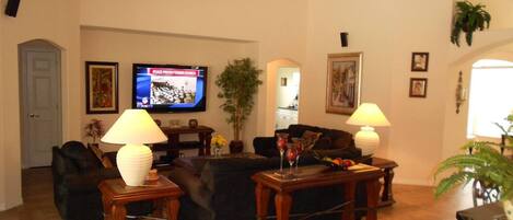 A living room with a television, two lamps, a sofa, a coffee table, and a door.