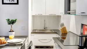 Eine moderne Küche mit weißen Schränken, einer Edelstahlspüle und einem eingebauten Backofen.