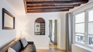 Ein Zimmer mit einer schwarzen Ledersofa, einer Holzbalkendecke, einem großen Fenster mit Blick und einer Tür zu einem anderen Raum.