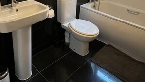 A bathroom with a white sink, toilet, and bathtub. - Lovely 2-bed Flat With Great Transport Links (London)