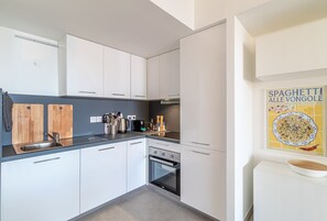A modern kitchen with white cabinets, a stainless steel sink, and a built-in oven. - Superb new 2-room Apartment -parking Border Monac (Beausoleil)