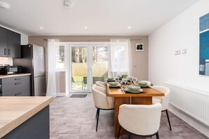 Eine moderne Küche mit Essbereich, einem großen Fenster und Blick auf den Garten.