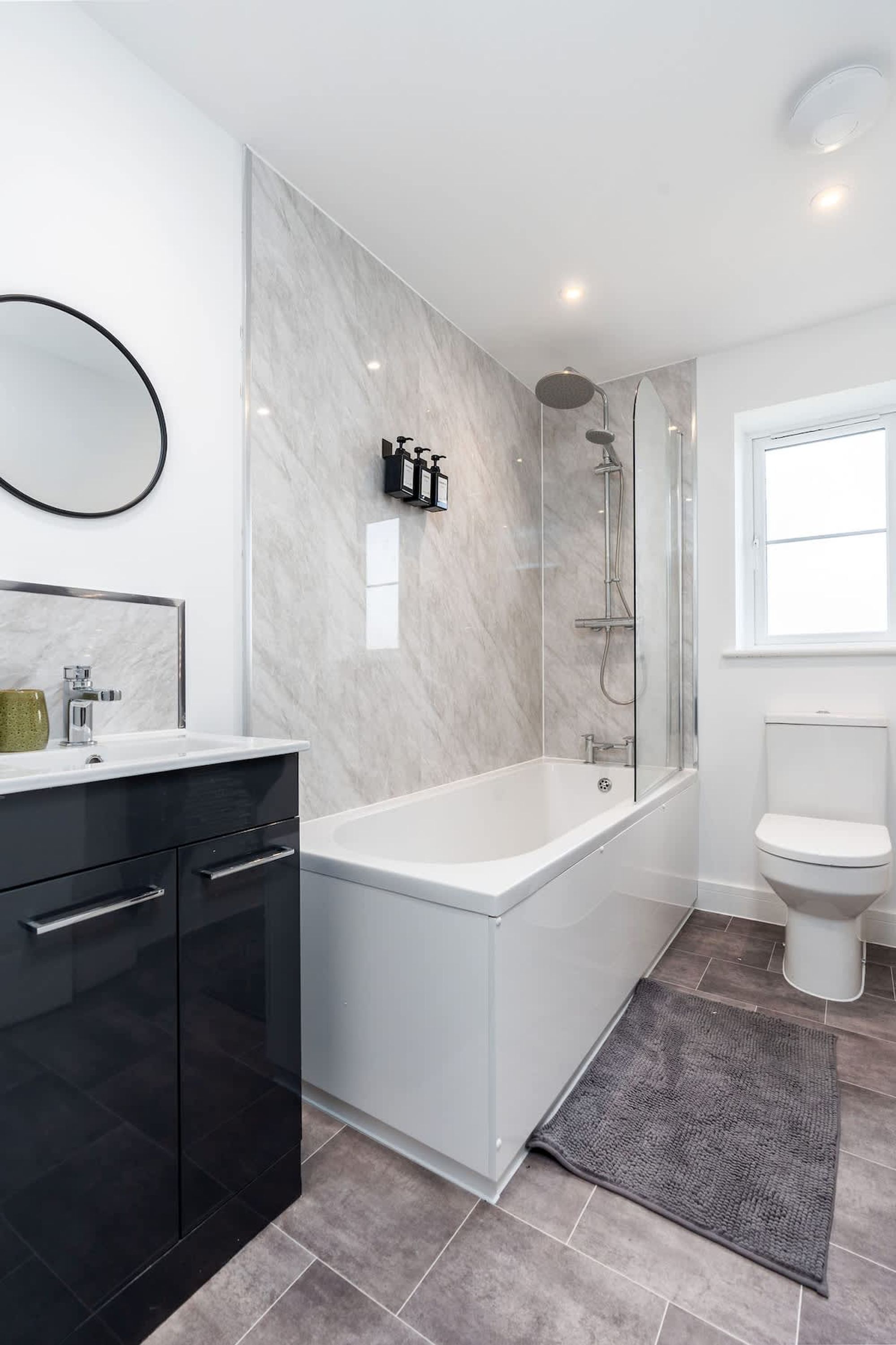 Un baño moderno con ducha de vidrio, inodoro blanco y mueble negro.