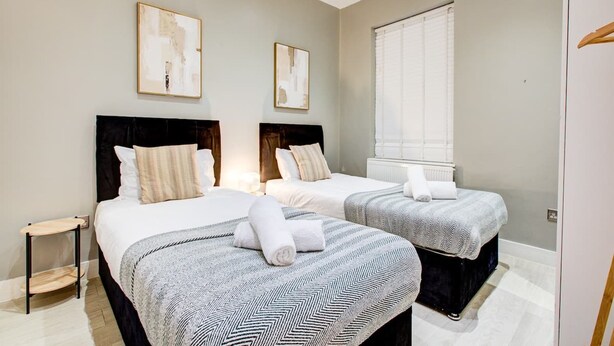 Habitació d'hotel amb dos llits, una petita taula auxiliar i obres d'art a les parets.