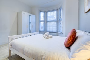 A bedroom with a bed, a wardrobe, and a window with blinds. - Perfect Booking 2 Bed Home in Leyton (London)