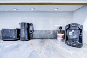 A kitchen with a coffee maker, a toaster, and a kettle on a marble countertop. - Perfect Booking 2 Bed Home in Leyton (London)