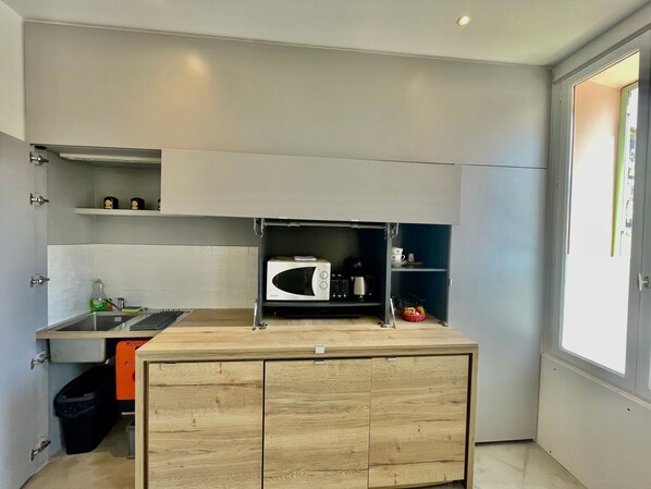 A compact kitchen with a microwave, coffee maker, and storage shelves. - Apartment Monaco Beach Grimaldi Forum (Beausoleil)