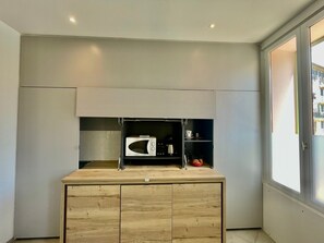 A compact kitchen with a microwave, kettle, and a small coffee maker on the countertop. - Apartment Monaco Beach Grimaldi Forum (Beausoleil)
