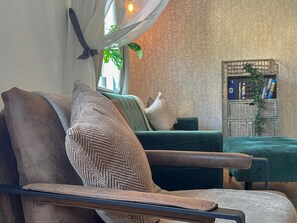 A modern living room with a sofa, a chair, a patterned wall, and a bookshelf. - Perfect Booking 3 Bed Home in Central Bracknell (Wokingham)