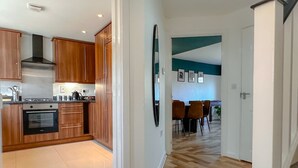 Een moderne keuken met houten kastjes, een inbouwoven en een rvs afzuigkap.
