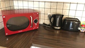A red microwave, a black coffee maker, and a toaster on a kitchen counter. - Spacious 2-bed Flat by Stockwell Station (London)