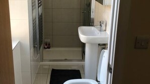 A bathroom with a toilet, sink, and shower area. - Spacious 2-bed Flat by Stockwell Station (London)