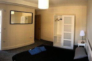 Quarto com cama, guarda-roupa, espelho e mesa de cabeceira com abajur.