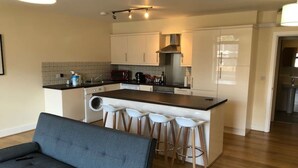 A modern kitchen with a central island, white cabinets, and a built-in microwave. - Spacious 2-bed Flat by Stockwell Station (London)
