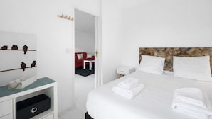 Een hotelkamer met een bed, nachtkastje, dressoir en spiegel.